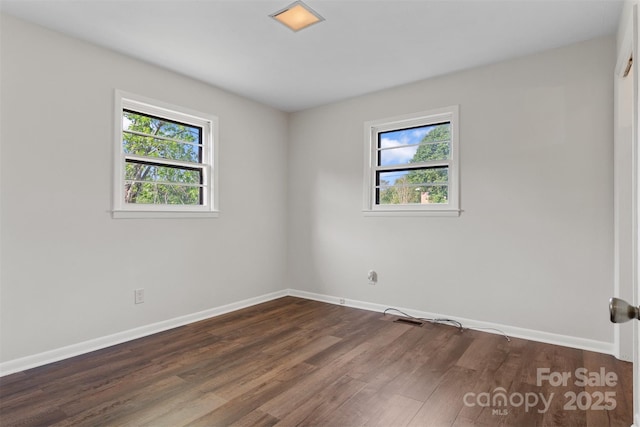 unfurnished room with baseboards and dark wood-style floors