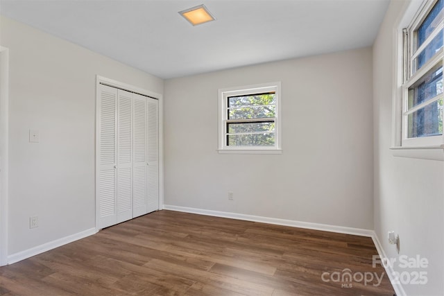 unfurnished bedroom featuring baseboards, a closet, and wood finished floors