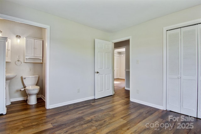 unfurnished bedroom featuring dark wood-style flooring, baseboards, and a closet