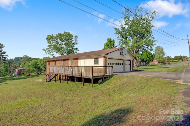 exterior space with a detached garage, a deck, brick siding, and a front yard