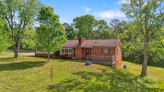 view of front facade featuring brick siding, a deck, a chimney, and a front yard