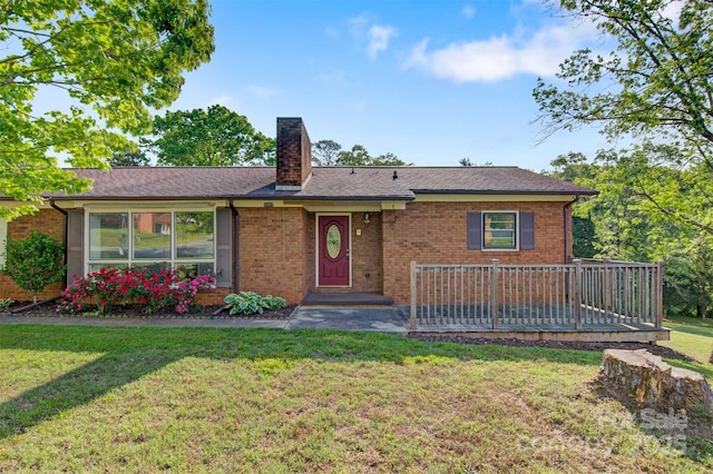 ranch-style house with brick siding, a front lawn, a wooden deck, and a chimney