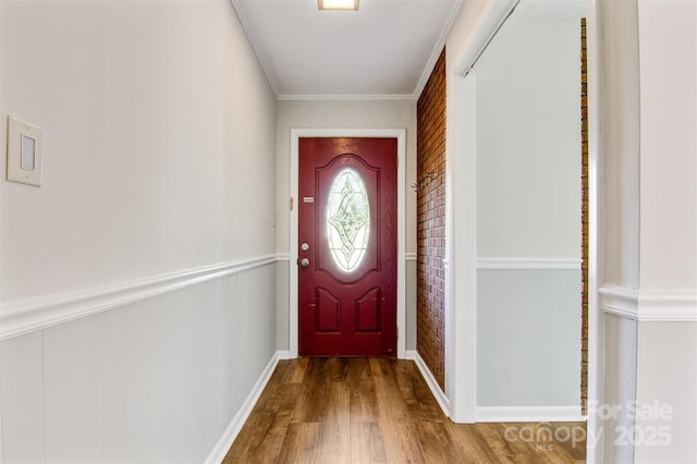 doorway to outside with crown molding, baseboards, and wood finished floors