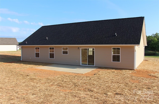 rear view of property with a shingled roof and a patio area