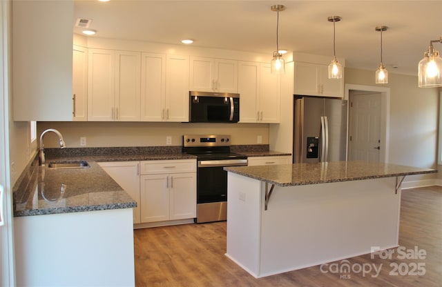 kitchen featuring white cabinets, stainless steel appliances, a sink, and light wood-style floors