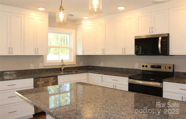 kitchen featuring stainless steel appliances, white cabinetry, a sink, and dark stone countertops