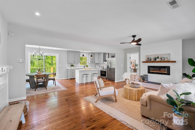 75 White Pine Dr, Fletcher, NC 28732 - living room featuring light wood-style floors, a glass covered fireplace, ceiling fan with notable chandelier, baseboards, and visible vents