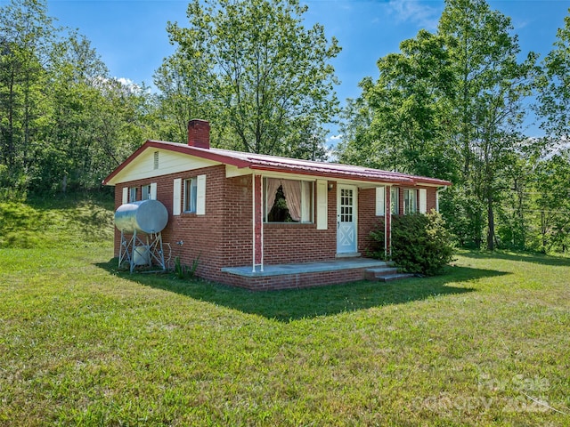 single story home featuring a front lawn, a chimney, and brick siding