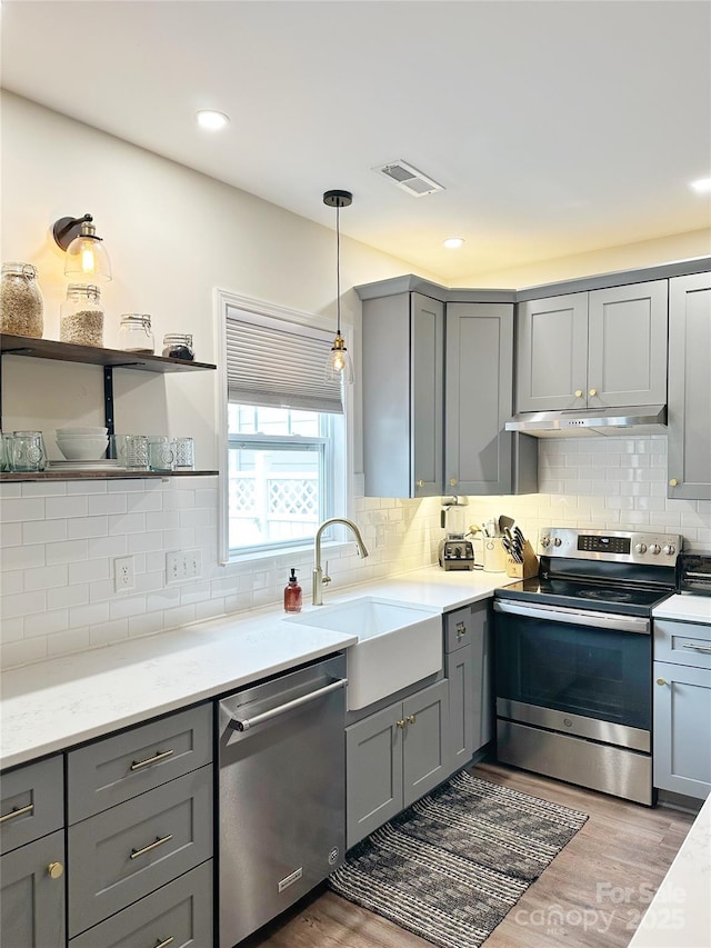240 Faust Rd, Davidson, NC 28036 - kitchen featuring appliances with stainless steel finishes, gray cabinets, under cabinet range hood, a sink, and wood finished floors