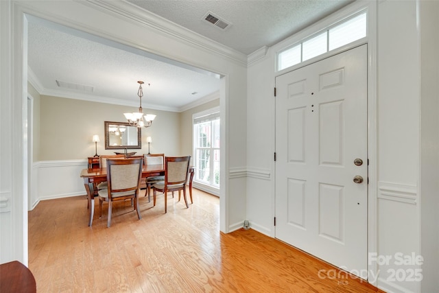 entryway featuring visible vents, a healthy amount of sunlight, light wood finished floors, and a notable chandelier