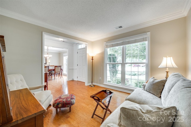 living area with a notable chandelier, light wood-type flooring, crown molding, visible vents, and a textured ceiling