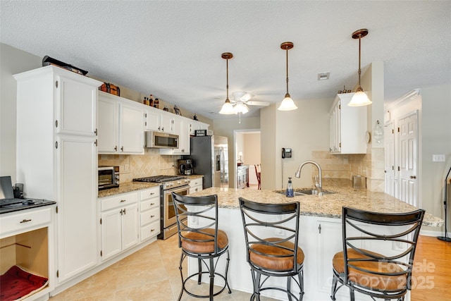 kitchen with stainless steel appliances, backsplash, a peninsula, and a sink