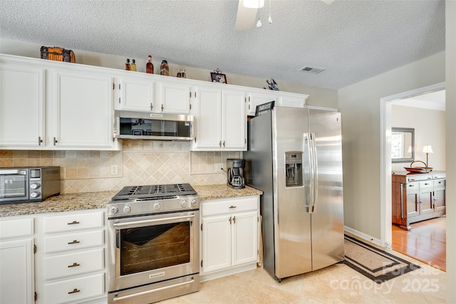 kitchen featuring light stone counters, tasteful backsplash, white cabinets, appliances with stainless steel finishes, and a toaster