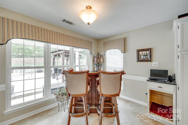 dining room featuring a wealth of natural light, visible vents, baseboards, and a textured ceiling