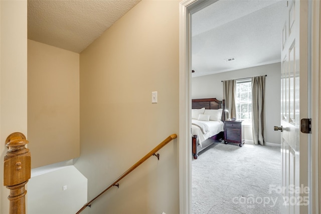bedroom with a textured ceiling, visible vents, baseboards, and carpet floors