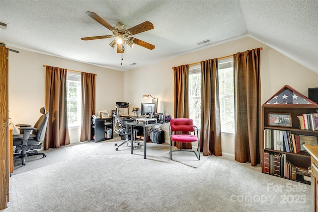 carpeted office space with lofted ceiling, a textured ceiling, visible vents, and ceiling fan