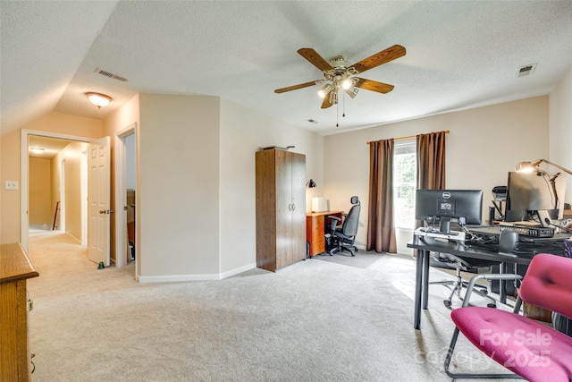 office featuring a textured ceiling, light colored carpet, visible vents, ceiling fan, and baseboards