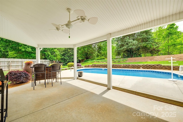 outdoor pool with fence, ceiling fan, and a patio area