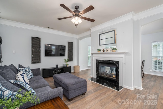 7905 Sedgebrook Dr E, Stanley, NC 28164 - living area featuring arched walkways, a ceiling fan, a premium fireplace, wood finished floors, and crown molding