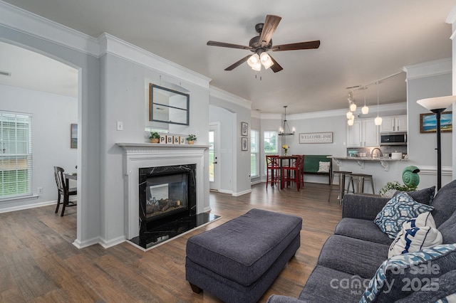 7905 Sedgebrook Dr E, Stanley, NC 28164 - living room with a fireplace, a ceiling fan, dark wood-style floors, arched walkways, and a chandelier