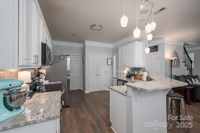 7905 Sedgebrook Dr E, Stanley, NC 28164 - kitchen with stainless steel microwave, white cabinetry, ornamental molding, decorative backsplash, and a kitchen bar