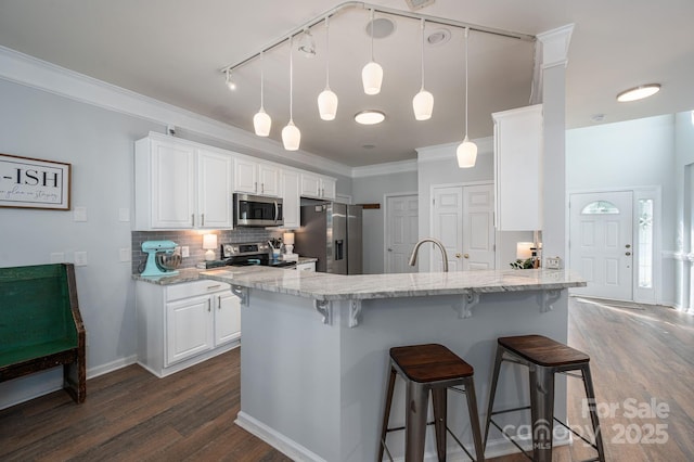 7905 Sedgebrook Dr E, Stanley, NC 28164 - kitchen with stainless steel appliances, dark wood-style flooring, a kitchen breakfast bar, decorative backsplash, and white cabinets
