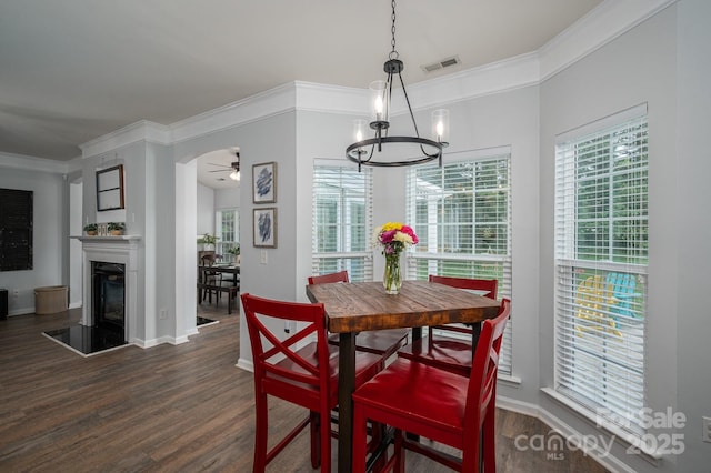 7905 Sedgebrook Dr E, Stanley, NC 28164 - dining area featuring a ceiling fan, dark wood-style floors, a chandelier, ornamental molding, and a glass covered fireplace