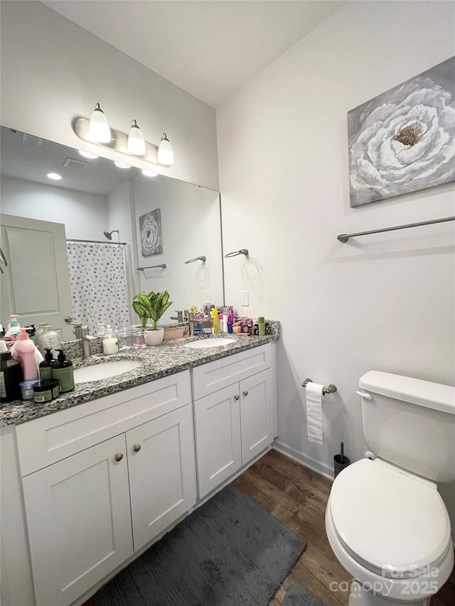 bathroom with toilet, walk in shower, a sink, and wood finished floors