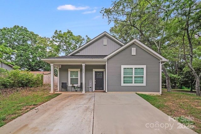 bungalow with fence, covered porch, and board and batten siding