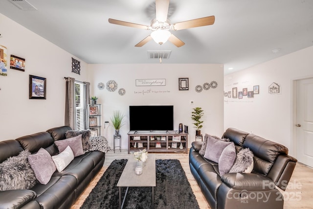 living room with visible vents, a ceiling fan, and light wood-type flooring