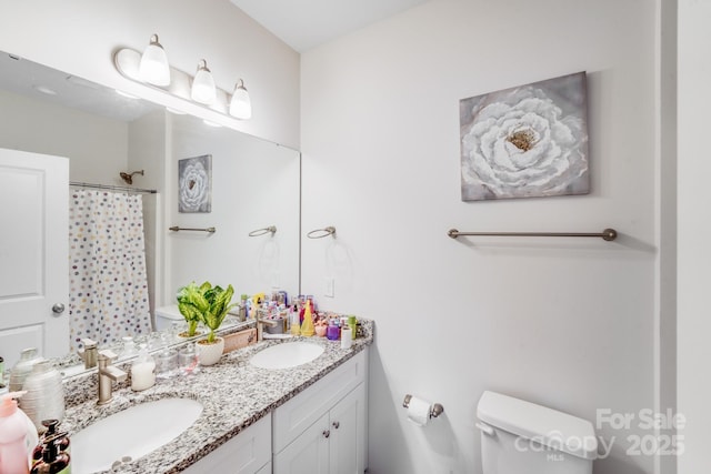full bathroom with double vanity, a sink, curtained shower, and toilet
