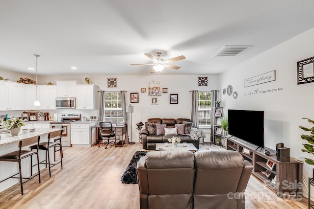 living room with a ceiling fan, light wood-style flooring, and visible vents