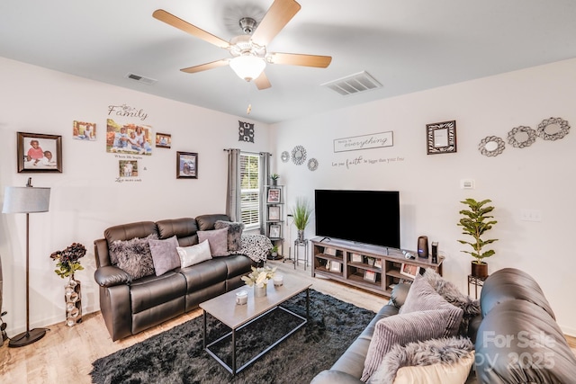living room featuring visible vents, a ceiling fan, baseboards, and wood finished floors