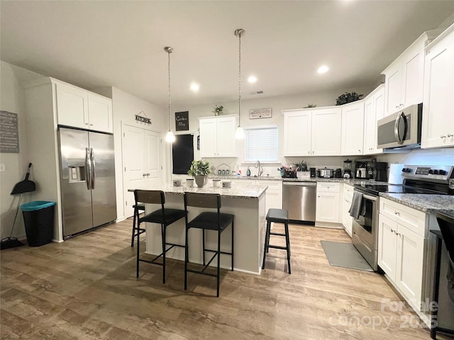 kitchen featuring a breakfast bar, a sink, stainless steel appliances, recessed lighting, and a kitchen island