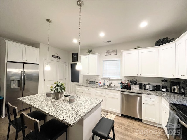 kitchen with a sink, appliances with stainless steel finishes, a breakfast bar area, and visible vents
