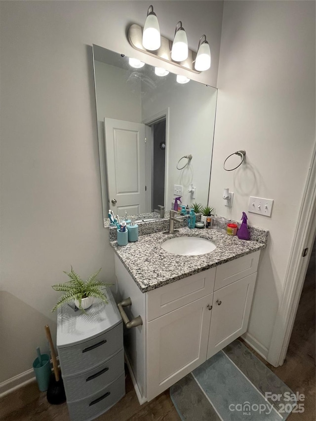 bathroom featuring baseboards, wood finished floors, and vanity