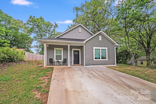 bungalow-style house featuring a porch, board and batten siding, and fence
