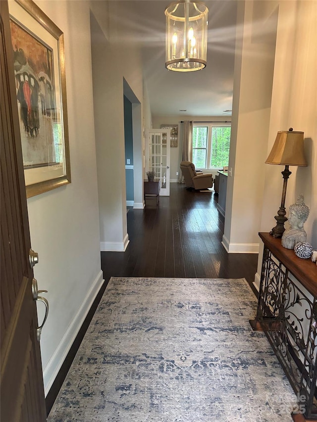 entryway with a notable chandelier, hardwood / wood-style floors, and baseboards