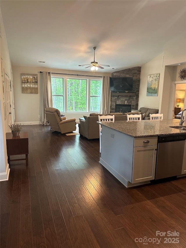 living room featuring dark wood finished floors, ceiling fan, visible vents, and a fireplace