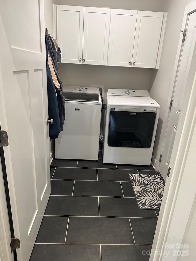 laundry area featuring washing machine and dryer, cabinet space, and dark tile patterned floors