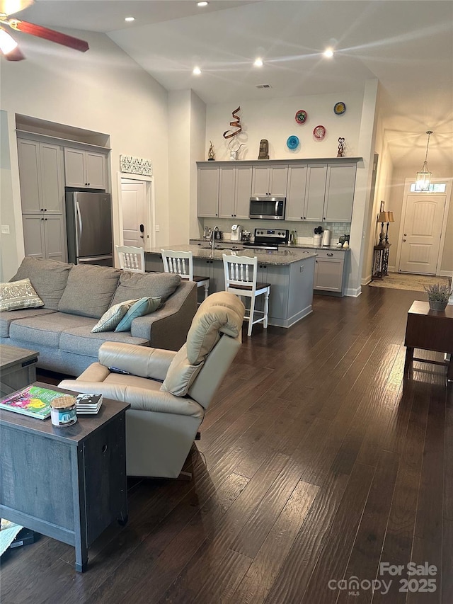 living area featuring recessed lighting, high vaulted ceiling, ceiling fan, and dark wood-style flooring