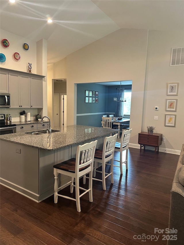 kitchen featuring a sink, a kitchen bar, visible vents, stone countertops, and appliances with stainless steel finishes