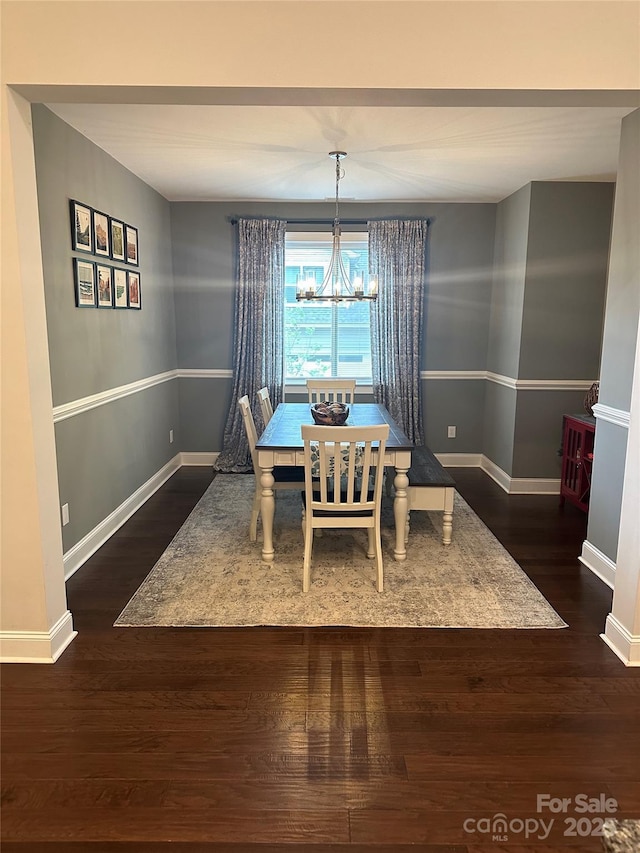 dining room featuring baseboards, wood finished floors, and an inviting chandelier
