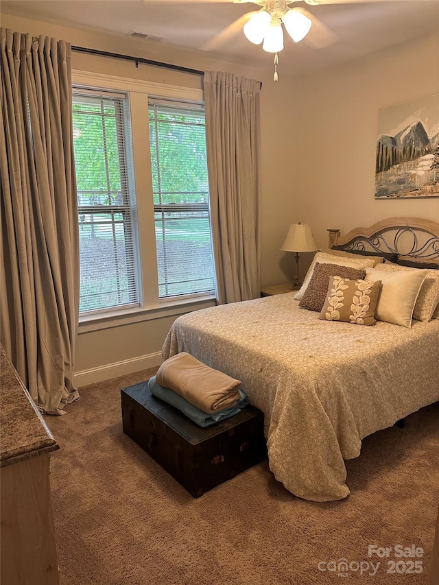 carpeted bedroom featuring visible vents, baseboards, and multiple windows