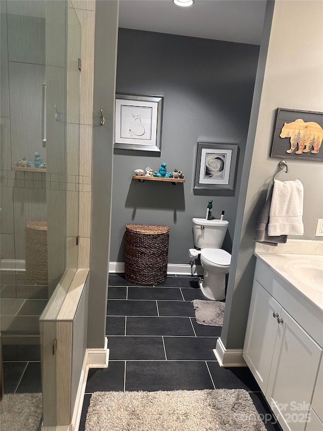 bathroom featuring tile patterned floors, toilet, vanity, baseboards, and a stall shower