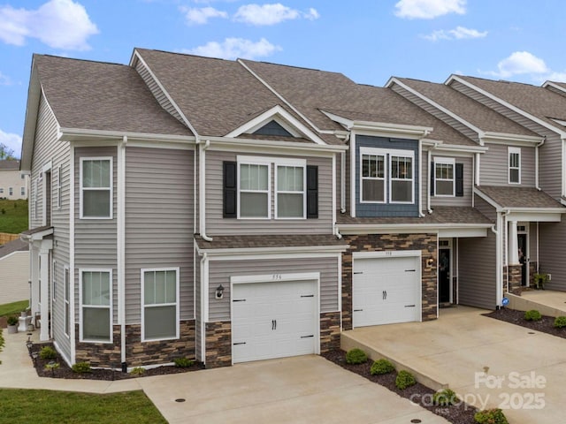 view of property with a garage, a shingled roof, concrete driveway, and stone siding