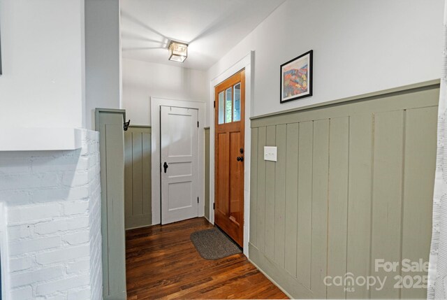 foyer entrance with dark wood-style floors and a wainscoted wall