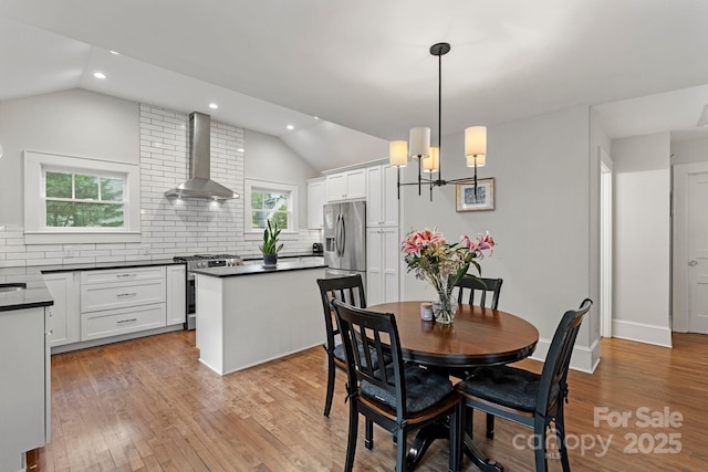dining room with a chandelier, recessed lighting, light wood-style floors, and lofted ceiling