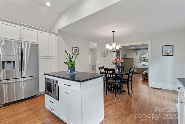 kitchen with light wood-style flooring, dark countertops, white cabinets, and appliances with stainless steel finishes