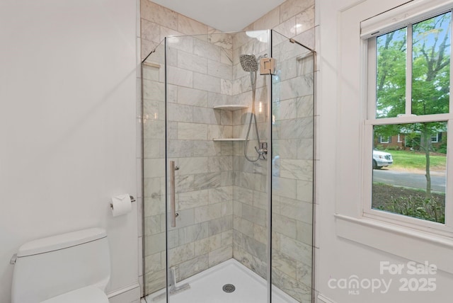 bathroom with toilet, a shower stall, and baseboards